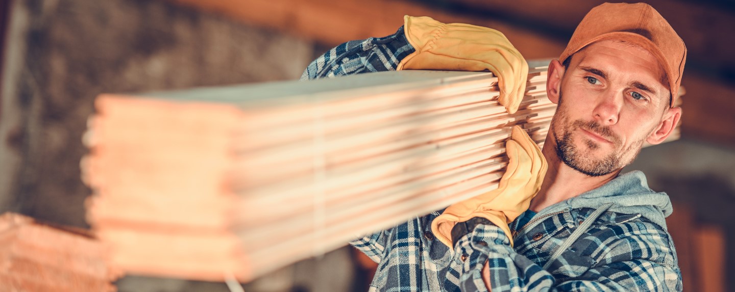 Contractor carrying wood at worksite.